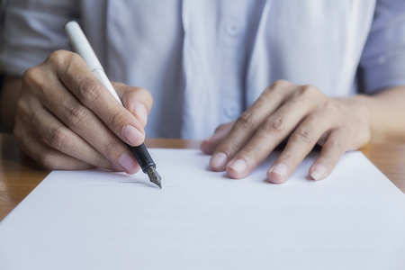 Businessperson Signing Contract,Women writing paper at the desk, man writing with pen and reading books at table,man Signing, Contract, Form. in office ,morning light ,selective focus.?の写真素材
