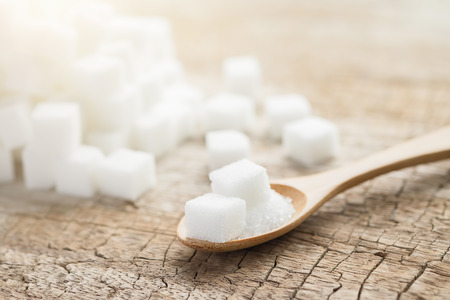 Bowl and scoop with white sand and lump sugar on wooden backgroundの写真素材
