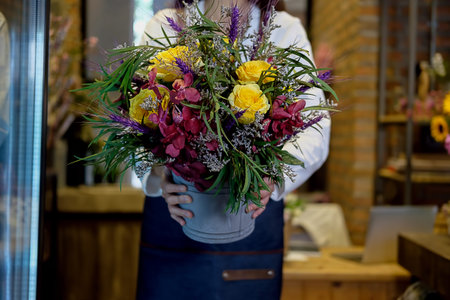 Cheerful charming young business owner flower shop store florist standing and holding flowers