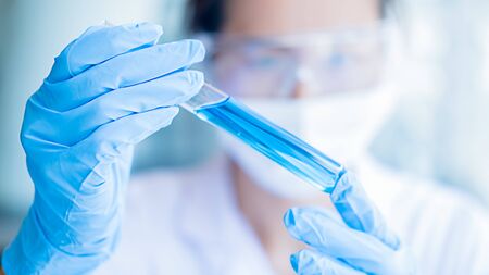 Medical or scientific researcher or man doctor looking at a test tube of clear solution in a laboratoryの写真素材