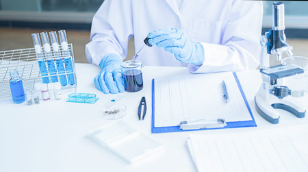 Medical or scientific researcher or man doctor looking at a test tube of clear solution in a...
