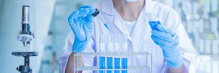 Medical or scientific researcher or man doctor looking at a test tube of clear solution in a laboratoryの写真素材
