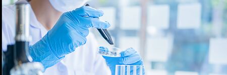 Medical or scientific researcher or man doctor looking at a test tube of clear solution in a laboratoryの写真素材