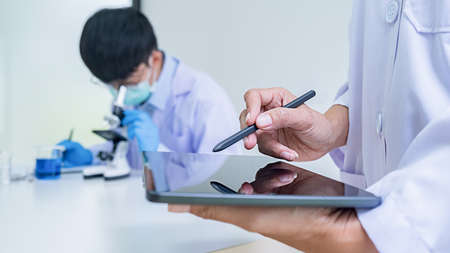 Medical or scientific researcher or man doctor looking at a test tube of clear solution in a laboratoryの写真素材