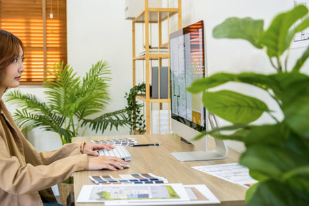 Side view of female graphic designer working with computer in creative office.の写真素材