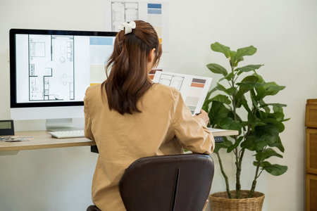 Rear view of businesswoman working on computer at desk in office