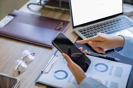 Businesswoman using mobile phone at desk in office, close-upの写真素材