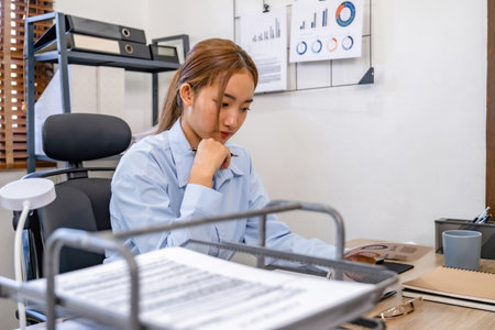 Young Asian businesswoman sitting at her desk in the office, she is tired of working.の写真素材