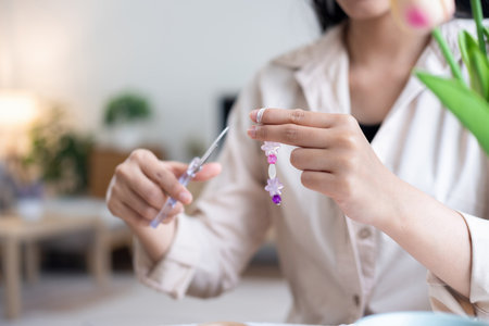 Young girl making handmade bracelets with fun and cheerfulnessの写真素材
