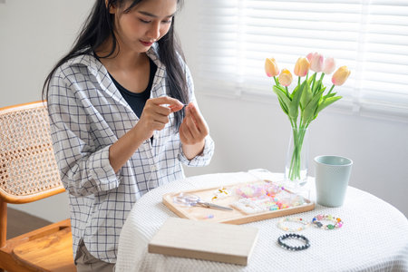 Young girl making handmade bracelets with fun and cheerfulnessの写真素材