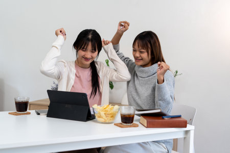 Female higher education student using laptop and studying book in home.の写真素材