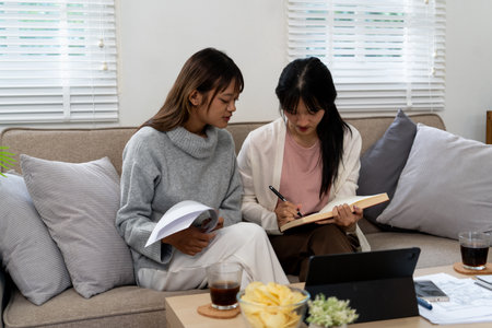 Female higher education student using laptop and studying book in home, Online learning.の写真素材