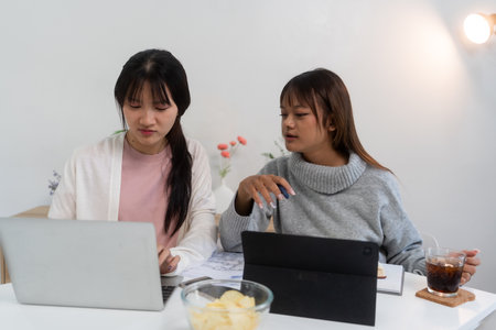 Female higher education student using laptop and studying book in home, Online learning.の写真素材