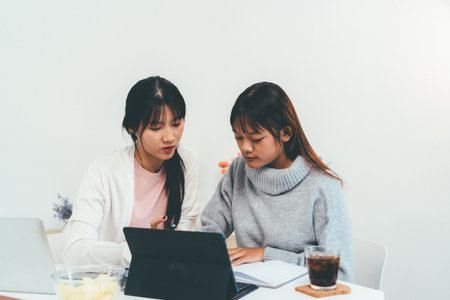 Female higher education student using laptop and studying book in home, Online learning.の写真素材