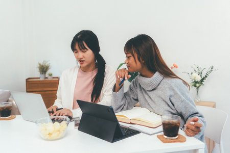 Female higher education student using laptop and studying book in home, Online learning.の写真素材