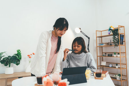 Female higher education student using laptop and studying book in home, Online learning.の写真素材