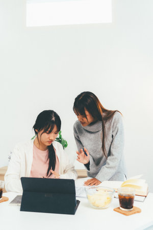 Female higher education student using laptop and studying book in home, Online learning.の写真素材