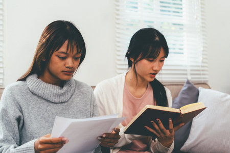 Female higher education student using laptop and studying book in home, Online learning.の写真素材