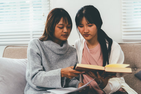 Female higher education student using laptop and studying book in home, Online learning.の写真素材