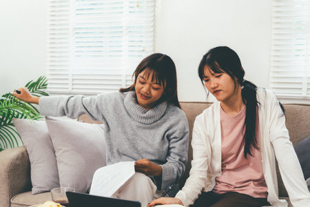 Female higher education student using laptop and studying book in home, Online learning.の写真素材