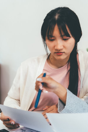 Female higher education student using laptop and studying book in home, Online learning.の写真素材