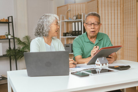 senior couple and documents with laptop for finance, budget planning or retirement annuity on sofa. Elderly man, woman or house with smile, computer or paperwork for pension fund or insuranceの写真素材