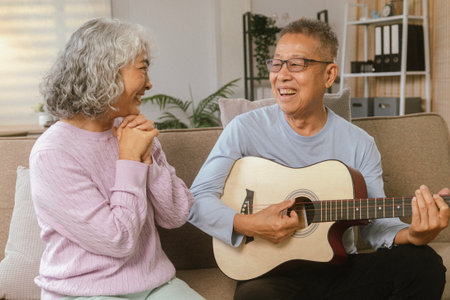Happy Senior Couple Enjoying Retirement Together Playing Musical Instruments at Home in Bright Sunshineの写真素材