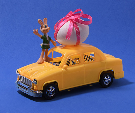 eggs on a toy car on a blue background with an empty card with the Hare Abstract retro concept.の写真素材