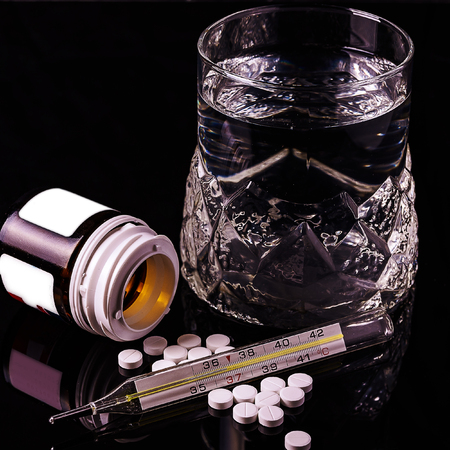 high-resolution photo on black background, disease treatment on which the thermometer glass water pill, for medicine, health, pharmacy, recipes,の写真素材
