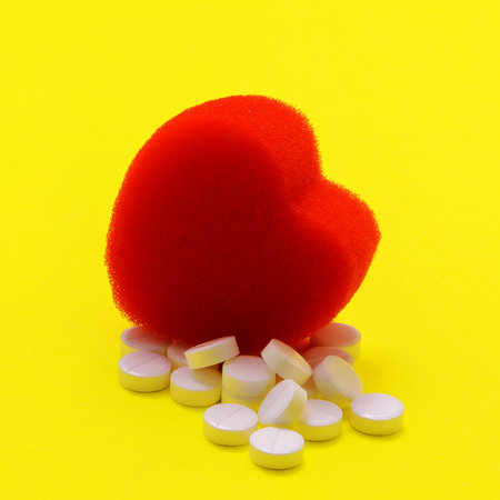 photo of tablets and heart on a yellow background, treatment of diseases in medicine for health,