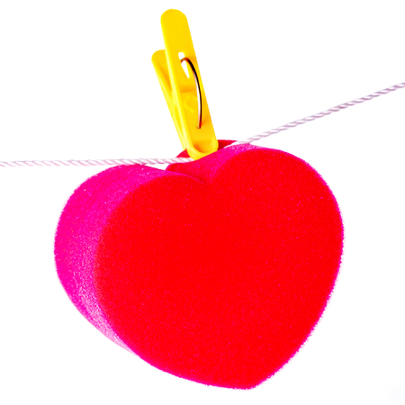 Red paper heart hanging on the yellow primako on the rope. Gray concrete background, horizontal orientation, space for text.の写真素材