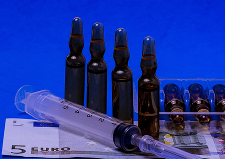 money for which to buy medical ampoules and a syringe isolated on a yellow background for the treatment of the heartの写真素材