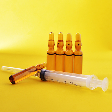 money for which to buy medical ampoules and a syringe, isolated on a yellow backgroundの写真素材