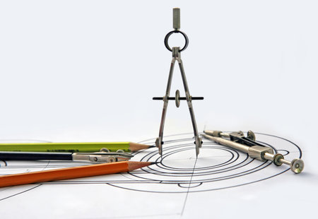 Compasses and pencils on the drawing on a white background