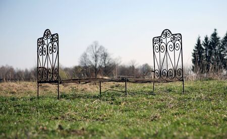 the forged bed stands on a green grass on a background skyの写真素材
