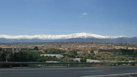 The mountains covered with snow and a valley in green treesの写真素材