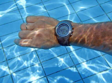 Man's hand with hours underwater in poolの写真素材