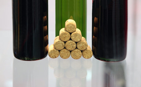 Bottles with wine and wine stoppers on a glass surfaceの写真素材