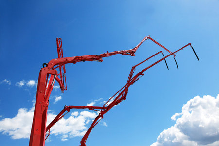 Fragments of concrete pumps booms on a blue sky