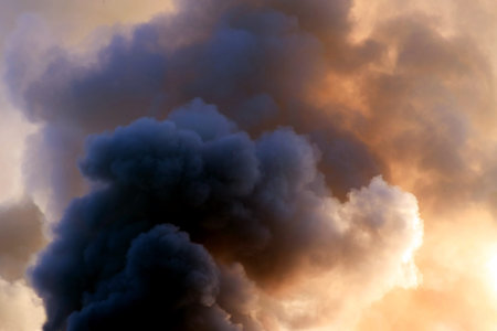 thick dark smoke in a fire against the sun