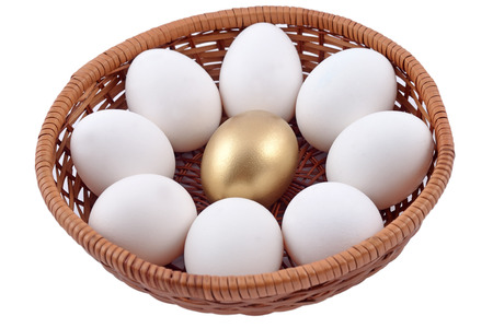 Golden egg and jast eggs in wicker bowl on a white backgroundの写真素材