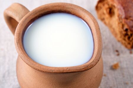 Ceramic jug with milk and fresh bread close-up, rustic styleの写真素材