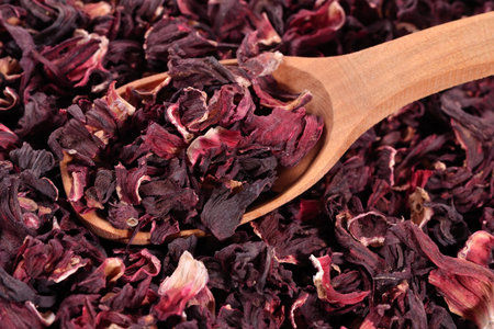 Dried petals of hibiscus in a wooden spoon close upの写真素材