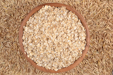 Top view of oatmeal flakes in a wooden bowl