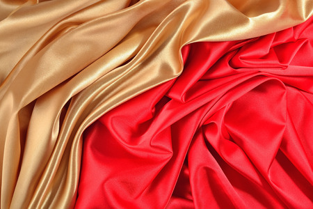 Background from golden and red satin fabric with picturesque foldsの写真素材