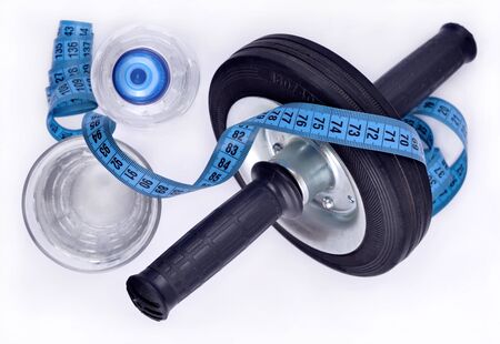 Bottle of water glass of water roller wheel for abdominals and measuring tape top viewの写真素材