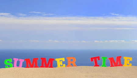 Summer time letters on a beach sand against the background of the sea