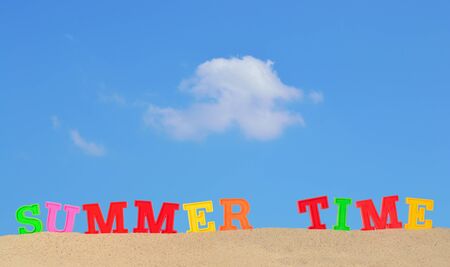 Summer time letters on a beach sand against the blue skyの写真素材