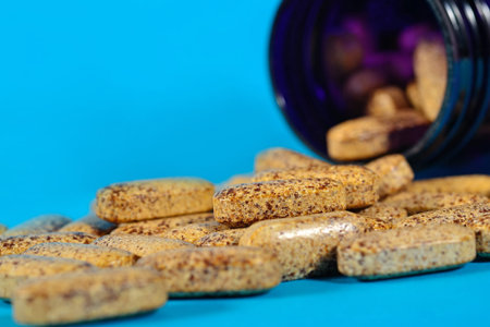 Pills spill out from bottle on a blue background
