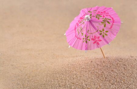 Cocktail umbrella close-up on a sand backgroundの写真素材